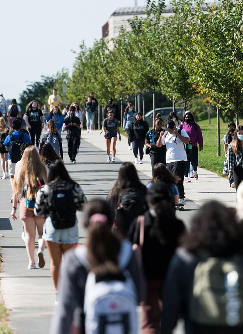 Crowd Students walk along walkway toward Uhall.