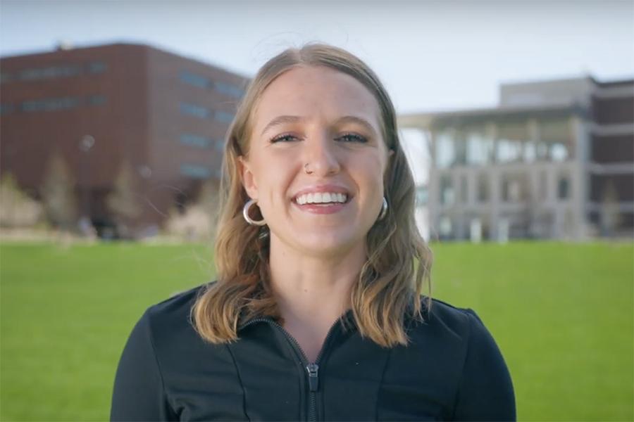 UMass Boston student Olivia standing on the quad smiling